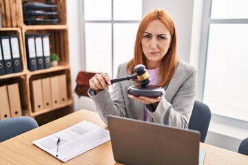 Poster - Young business woman using gavel skeptic and nervous, frowning upset because of problem. negative person.