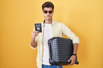 Sticker - Young hispanic man holding suitcase going on summer vacation holding italian passport skeptic and nervous, frowning upset because of problem. negative person.