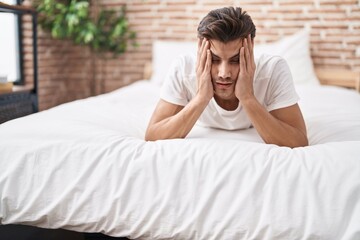 Wall Mural - Young hispanic man stressed lying on bed at bedroom