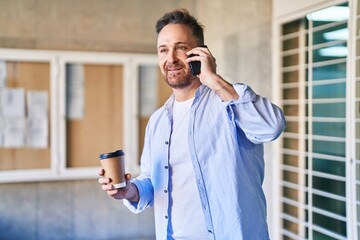 Sticker - Young caucasian man talking on the smartphone drinking coffee at street