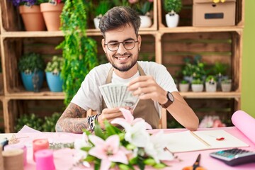 Canvas Print - Young hispanic man florist smiling confident counting dollars at flower shop