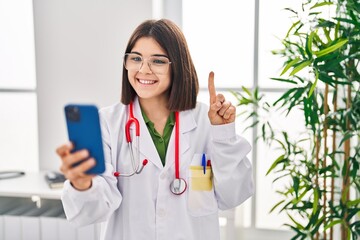 Poster - Young hispanic doctor woman working on online appointment smiling with an idea or question pointing finger with happy face, number one