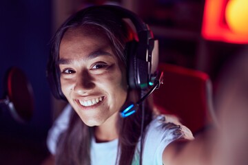 Wall Mural - Young beautiful hispanic woman streamer smiling confident make selfie by camera at gaming room