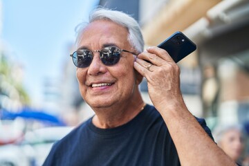 Wall Mural - Middle age grey-haired man smiling confident listening audio message by the smartphone at street