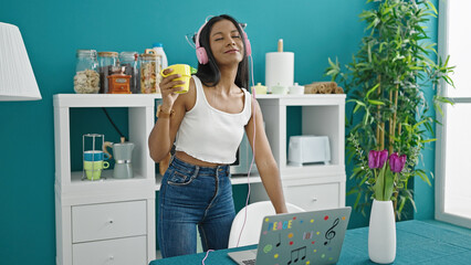 Wall Mural - African american woman listening to music drinking coffee at dinning room