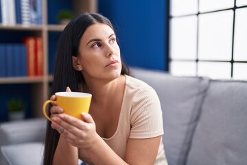 Canvas Print - Young beautiful hispanic woman drinking coffee with serious expression at home