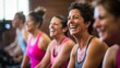 Group of women of different ages and races during cycling workout. Group fitness classes on exercise bikes. Workouts for any age. Be healthy in any age. Photo against a bright, gym studio background. 
