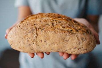 hands with fresh baked loaf rye wheat bread