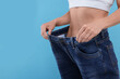 © New Africa - Slim woman wearing big jeans on light blue background, closeup and space for text. Weight loss