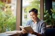 © A Denny Syahputra - Asian man reading book in cafe, sitting near window, copyspace