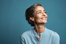 Close Up Portrait Of A Happy Smiling Middle Aged Woman Looking Up Over Blue Background