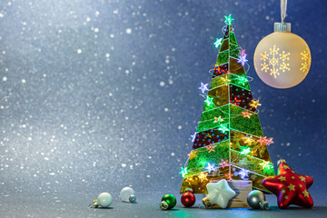 Sticker - christmas tree decorated by multicolored star lights with new year ornaments on blue blurred background.