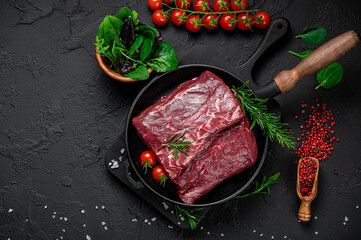 Wall Mural - Raw organic marbled beef with spices on a wooden cutting board on a black slate, stone or concrete background.