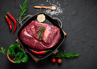 Wall Mural - Raw organic marbled beef with spices on a wooden cutting board on a black slate, stone or concrete background.