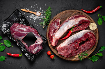 Wall Mural - Raw organic marbled beef with spices on a wooden cutting board on a black slate, stone or concrete background.