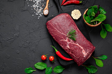 Wall Mural - Raw organic marbled beef with spices on a wooden cutting board on a black slate, stone or concrete background.