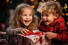 Portrait Of Overjoyed Boy And Girl Opening New Year's Gift. New Year's Morning And Children's Enthusiasm For Gifts. Blurred Living Room Interior With Christmas Tree.