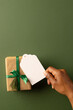 Vertical image of african american woman's hand holidng tag with copy space and christmas present