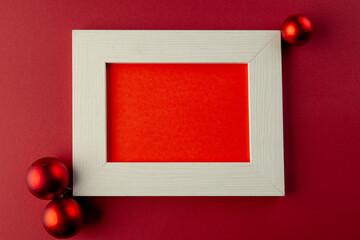 Poster - Red baubles christmas decorations and wooden frame with copy space on red background