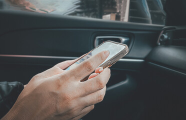 Close-up of a passenger sitting in a car using a mobile phone. Concept of viewing GPS navigation systems, sending emails