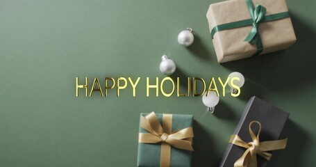 Poster - Happy holidays text in gold over christmas baubles and gifts on green background