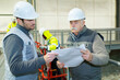 © auremar - senior engineer and colleague looking at papers in factory