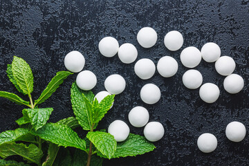 Wall Mural - Mint candies. Menthol bonbons and mint leaves on black table. Top view.