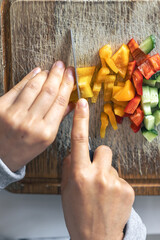 Wall Mural - A woman cuts vegetables on a cutting board.