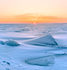 Wall Mural - Winter landscape. Snowdrifts on the ice surface during sunset.