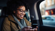 a closeup photo of African-American passenger sitting at back seat in a taxi smiling using smartphone app, taxi booking application, female model, young woman, casual outfit