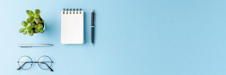 Overhead shot of modern office desktop with business accessories on blue background with copyspace. Flat lay