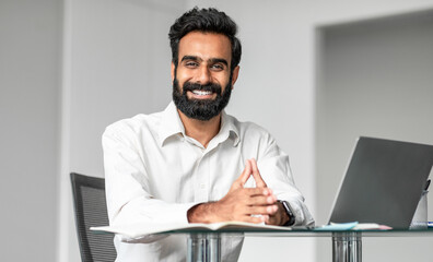 Aufkleber - Cheerful confident indian man business consultant working in office, sitting at workdesk in front of laptop and smiling