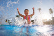 © Halfpoint - Little girl splashing water in the pool, playing in the water, having fun. Beach resort vacation by sea. Winter or summer seaside resort holiday.