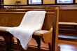 white prayer shawl draped over an empty synagogue chair
