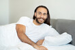 © Prostock-studio - Smiling Pleased Long-Haired Man Lying In Comfortable Bed