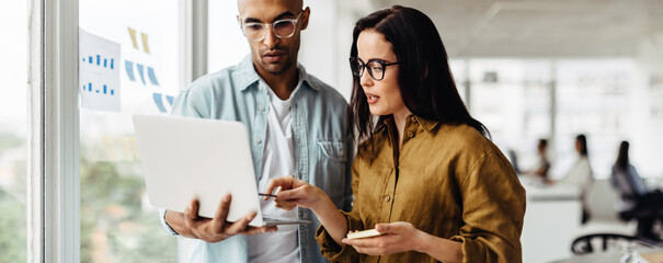 Poster - Business people standing in an office and using a laptop