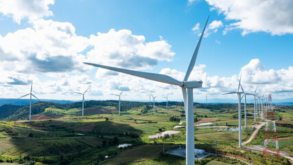 Wall Mural - Aerial view of Powerful wind turbine farm for pure energy production on beautiful clear blue sky with white clouds and wind farm background. Wind turbines for the generation of electricity