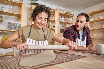 Wall Mural - Woman enjoying kneading clay with rolling pin in a ceramic workshop. Hobby and craft concept.