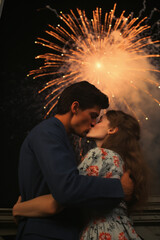  young couple in love kissing under colorful fireworks in the dark night sky on new years eve 4th of July cinematic setting in magazine cover editorial textured film look