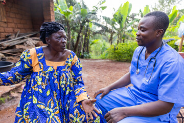 A doctor talks to his elderly patient during a home visit in an African village