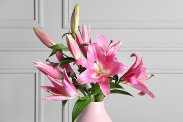 Poster - Beautiful pink lily flowers in vase against light wall