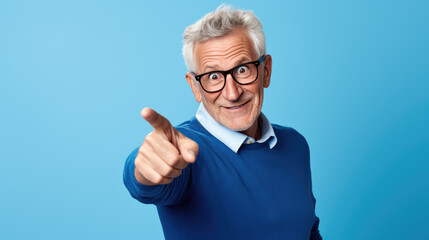 Wall Mural - Senior man pointing with hand and finger to the side looking at the camera.