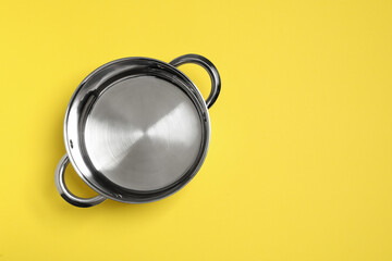 Wall Mural - Empty steel pot on yellow background, top view. Space for text
