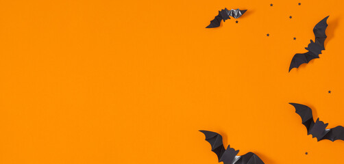 Wall Mural - Halloween holiday with party decorations, black paper bats on orange background. Halloween concept. Flat lay, top view, copy space