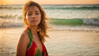 Beautiful green-eyed Caribbean woman, dressed in a green and red sarong, posing with a nostalgic look on the beach.