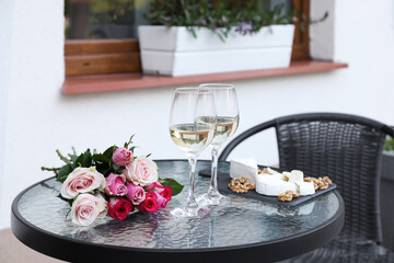 Canvas Print - Bouquet of roses, glasses with wine and food on glass table near house on outdoor terrace