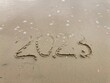 Jahreszahl 2023 vergänglich im Sand am Strand geschrieben