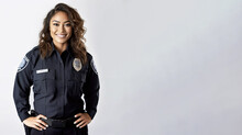 Mixed Race Woman Wearing Uniform, Police Officer Or Cop, Studio Portrait With Light Background, Banner Copy Space On Side. Generative AI