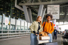 Happy Woman Friends With Luggage Trolley Waiting For Taxi Go To Hotel In The City Together At Airport Terminal. Attractive Girl Enjoy Travel On Holiday Vacation With Airplane And Public Transportation