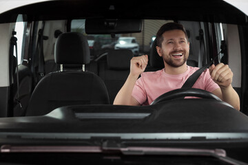 Wall Mural - Listening to radio. Handsome man enjoying music in car, view through windshield